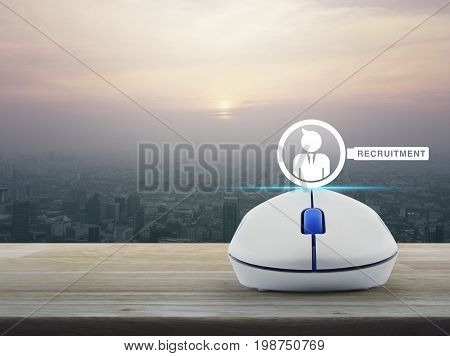 Businessman and magnifying glass icon with wireless computer mouse on wooden table over modern city tower at sunset vintage style Recruitment online concept