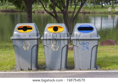 Color trash containers for seperate gabage. Trash bin along the way in park. Gabage seperate bin in park.
