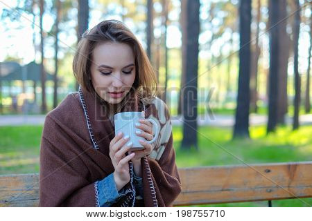 girl in a plaid drinking coffee in the park