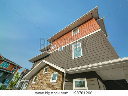 Side wall of brand new residential triplex townhouse on blue sky background. Family house for sale