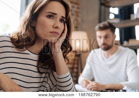 Thoughtful look. Depressed cheerless unhappy woman holding her chin and thinking about her problems while having a difficult period in life