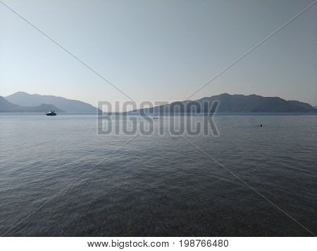 Beatiful sea summer panorama.  Beach scene at Pukka region, yachts, boats, mountains, shot at Marmaris, Turkey. blue sky, tourists in swimsuits, umbrellas, people resting, swimming