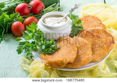 Tasty onion cutlet fresh vegetables (tomatoes parsley green onions) and sour cream on green wooden table. The concept of dietary and vegetarian food. Healthy food