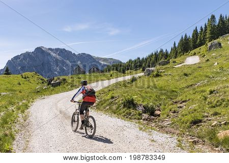 Mountainbiker on a gravel road on Nassfeld in Carnic Alps with view to mountain Rosskofel