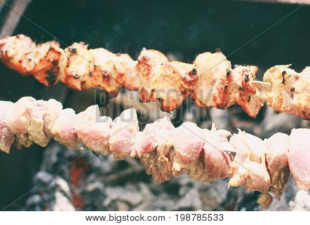 raw kebab grilling on metal skewer. Raw meat roasting at barbecue. BBQ fresh beef and chicken meat chop slices. Grill on charcoal and flame picnic street food