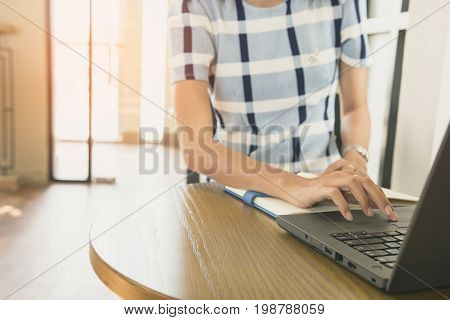 Businesswoman working from home via portable computer hipster girl freelancer writing on keyboard flare light