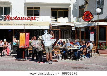 BUGIBBA, MALTA - MARCH 28, 2017 - Tourists relaxing at a restaurant in Bugibba Square during the Springtime Bugibba Malta Europe, March 28, 2017.