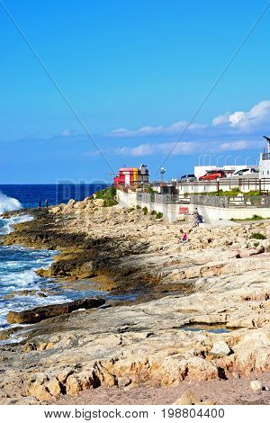 BUGIBBA, MALTA - MARCH 28, 2017 - Tourists relaxing on the rocky shoreline Bugibba Malta Europe, March 28, 2017.