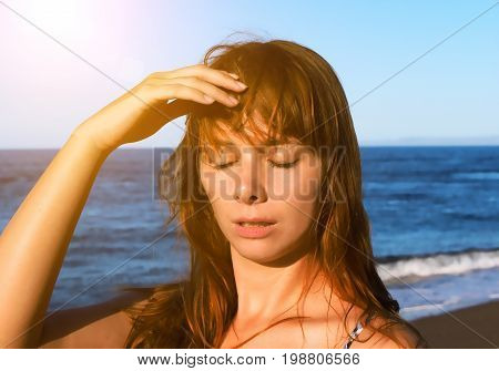 Young woman with heatstroke. Health problem on vacation. Medicine on vacation. Dangerous sun. Beach life. Sunstroke on hot beach. Girl under sun. Red hair girl on beach by sea. Holiday health care