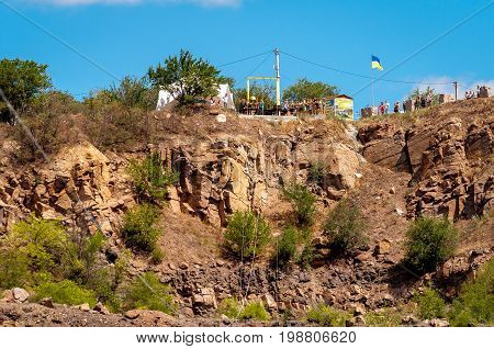 Ukraine Migea - July 30 2017: Zipline. Starting platform on a high rock. The man in the equipment slides on a steel cable. Trolley Track Over the lake. Extreme and active rest.