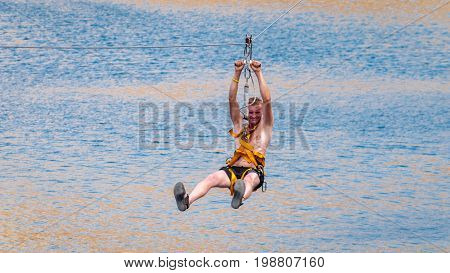 Ukraine Migea - July 30 2017: Zipline. The man in the equipment slides on a steel cable. Trolley Track Over the lake. Extreme and active rest.