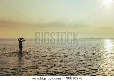 young pretty woman at sunrise in the lake water