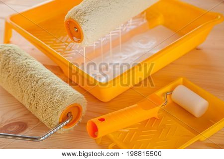 Paint roller brush at the bucket with white paint on wooden background