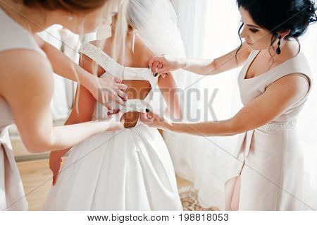 Bridesmaids Helping Gorgeous Bride To Dress Up And Get Ready For Her Wedding Ceremony.