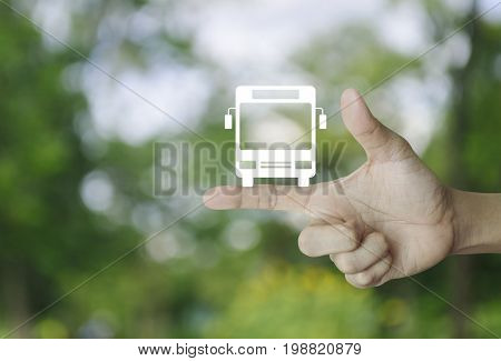 Bus flat icon on finger over blur green tree background Business transportation service concept