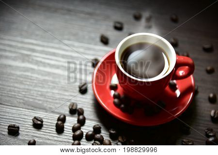 Red cup coffee with stream vapor and coffee bean on wood table selective focus on edge of cup Drinking concept