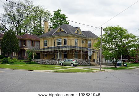 CADILLAC, MICHIGAN / UNITED STATES - MAY 31, 2017: A charming yellow brick Victorian mansion, with a wraparound porch and elegant stonework, in the Courthouse Hill Historic District of Cadillac, Michigan.