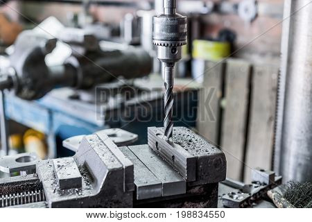 Drilling machine. The drill bit is installed in the drill chuck. Machine vice, metalworking shop.