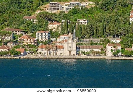 Prcanj - a small town along the Bay of Kotor Montenegro. A part of the waterfront that consists of a long line of stone villas and churches separated by gardens and olive orchards.