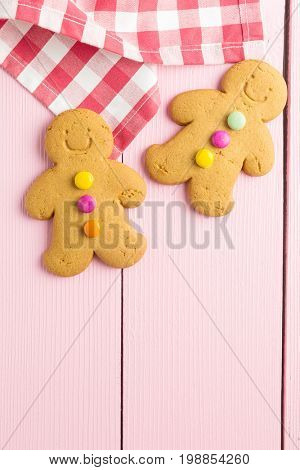 Two gingerbread men on colorful wooden table. Top view. Xmas gingerbread.