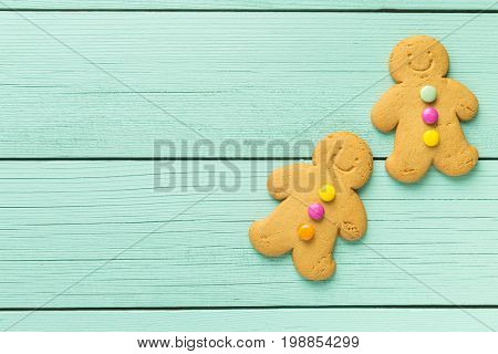 Two gingerbread men on colorful wooden table. Top view. Xmas gingerbread.