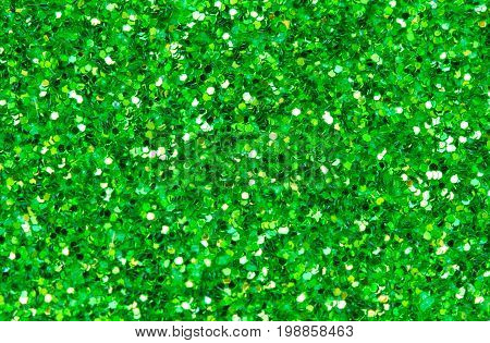 Green abstract background. Green glitter closeup photo. Green shimmer wrapping paper. Sparkling glitter festive backgrop. Christmas or New Year template. Glitter texture macrophoto. Shiny green card