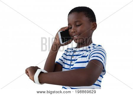 Boy looking at his smart watch while talking on mobile phone against white background