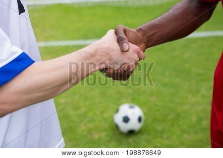 Cropped image of soccer player doing handshake while standing on playing field