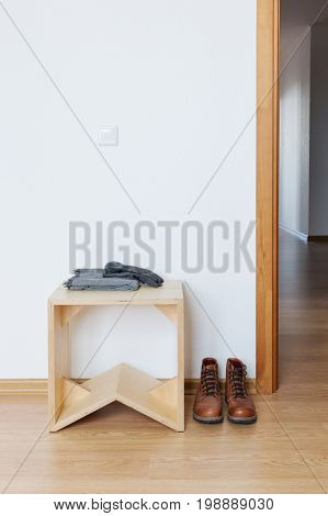 White empty anteroom with wooden stool and leather boots