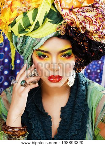 beauty bright woman with creative bright make up, many shawls on head like cubian, ethno look closeup