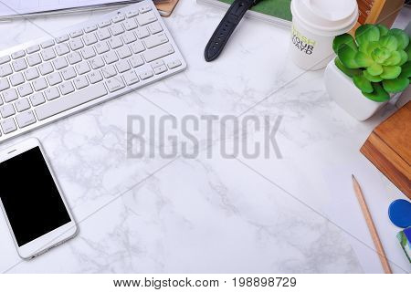 smartphone Kayboard and office supplies on marble background