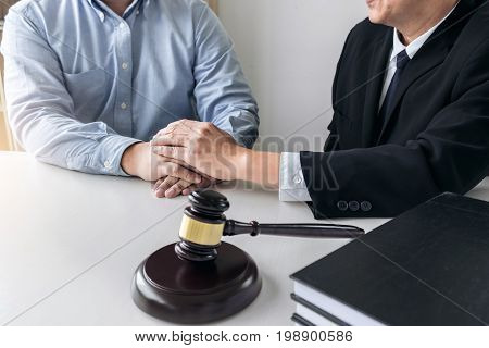 Image of Male lawyer or judge help encourage client customer working with gavel and Law book report the case on table in modern office Law and justice concept.