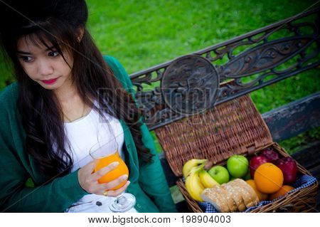 Young Woman Holding Glass Drinking Orange Juice With Friuits Basket. Top View From Back. Healthy Con