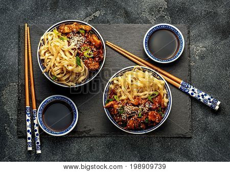 Chicken teriyaki on dark background with balsamic sauce and sesame seeds. Asian food. Noodles, chicken and soy sauce. Top view.