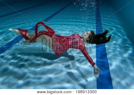 Dress of the woman flutters under the water she dives underwater.