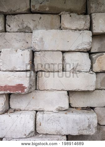 White calcium silicate bricks piled on top of each other. Old, cracked and chipped brick built, rough stack. The texture of the brick close-up.