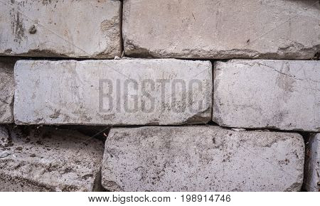 White calcium silicate bricks piled on top of each other. Old, cracked and chipped brick built, rough stack. The texture of the brick close-up.