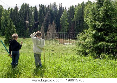 Two boys stand side by side talking about the beauty of nature: meadows forests rivers.