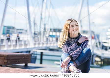 outdoor portrait of young happy smiling teen girl on marine background on a sunny day, auckland central wharf, new zealand