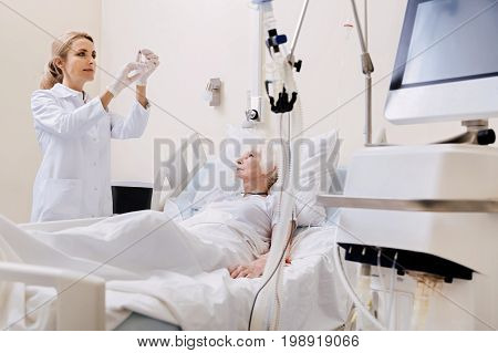 Lets make you healthy again. Young neat experienced woman using sterile equipment for making and injection and treating her patients disease