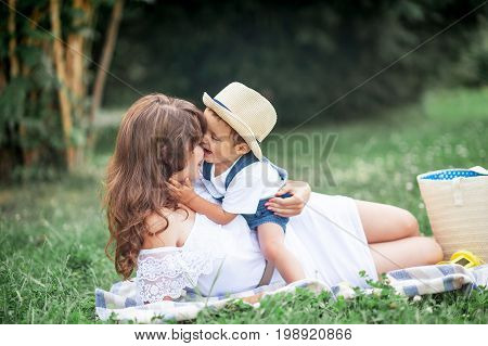 Mother And Young Son Played On Grass. Happy Family Walks In The Park. Mom And Young Son Eating Fruit