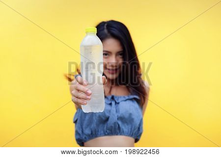 Young girl asian holding pure water bottle on yellow background