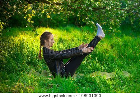 Woman Doing Yoga Outdoors On Green Grass
