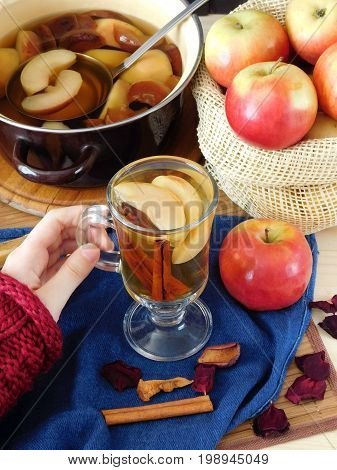 Apple compote in an Irish mug. Female hand is holding a glass of warm compote