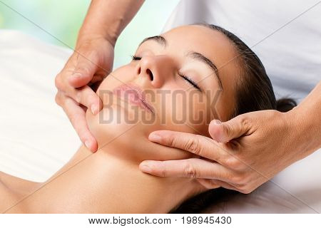 Close up facial massage on female chin.Therapist applying revitalizing cream on face.