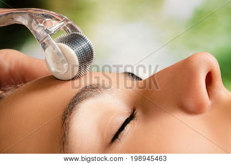 Macro close up portrait of woman having beauty skin treatment.Therapist preparing skin with derma roller.