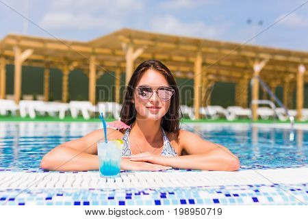 Portrait Of Young Sexy Girl Relaxing At The Edge Of The Swimming Pool., Wearing Swimsuit And Drinkin