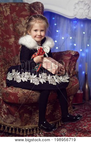 Happy little girl with a gift near the Christmas tree