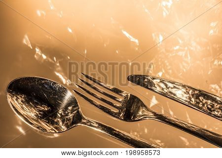 Fork, spoon and knife with reflections and light effects