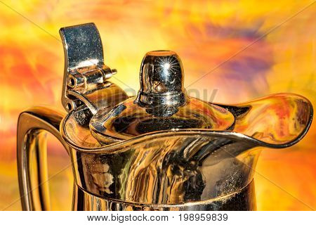 Shiny coffee pot in front of colorful background
